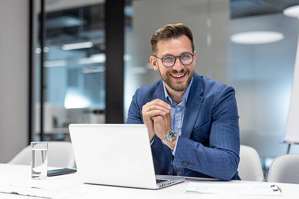 istock Businessman smiling while working on laptop in office 2234948605