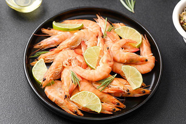 istock Cooked shrimp with lime and herbs on black plate for tropical seafood or restaurant menu concept 2234948957