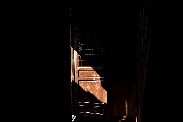 Large gate with a fence on the other side. The gate is open, and the sun is shining through the fence, creating a shadow on the ground