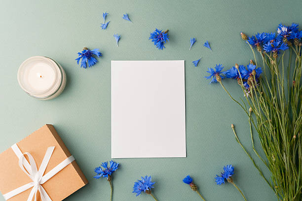 istock Card with candle, gift box and cornflowers on green background 2234953042