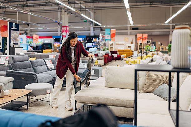 istock Asian female customer holding fabric samples, deciding between different upholstery textures and tones in a modern living room furniture section 2234955259
