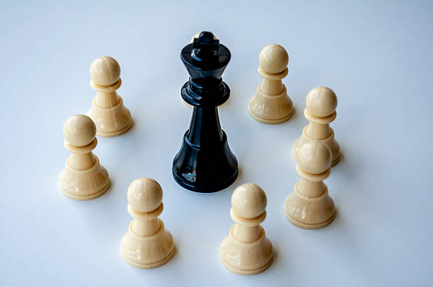 istock A group of beige chess pawns positioned around a black king piece on a light surface creating a symbolic leadership and unity concept. 2234960280