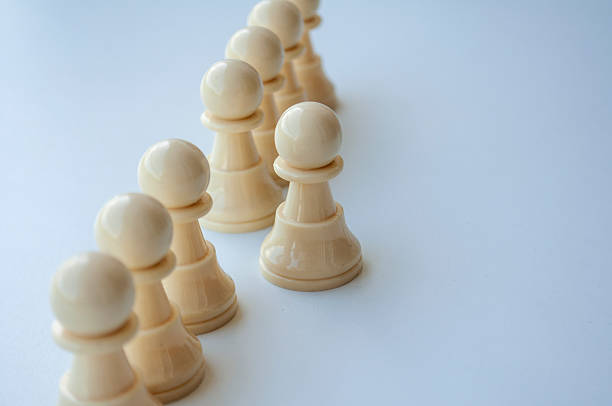 istock Several plain beige wooden dolls aligned vertically on a white surface illustrating simplicity and uniformity 2234960322