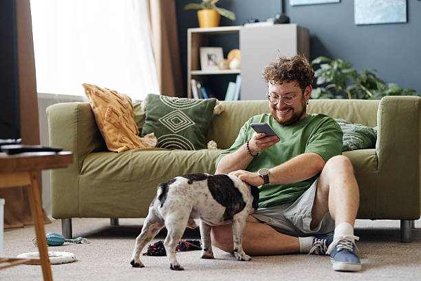 istock Young Adult Man Sitting on Floor Smiling While Using Smartphone 2234960914