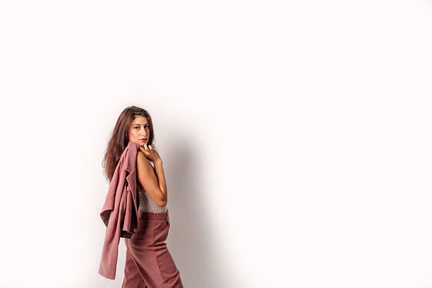 Studio shot of a young businesswoman posing with her jacket on her shoulder on a white background