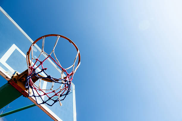 Basketball board with basket hoop against blue sky