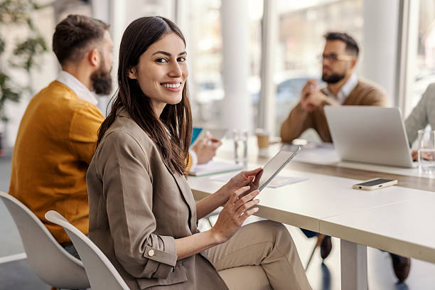 istock Confident Young Woman Holding Tablet During Discussion with Colleagues in Bright Modern Office 2234968082