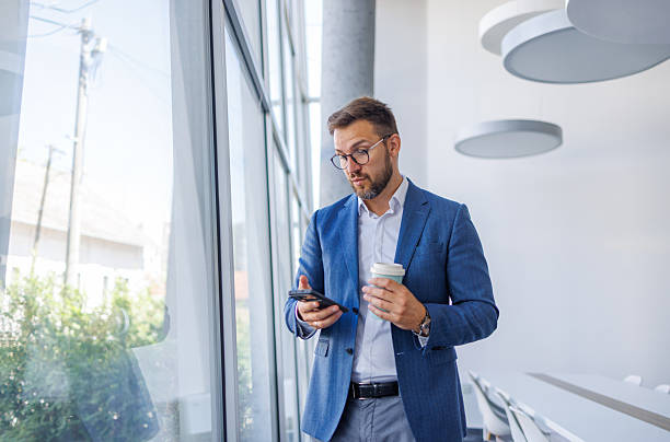 istock Businessman using smartphone and drinking coffee in office 2234968696