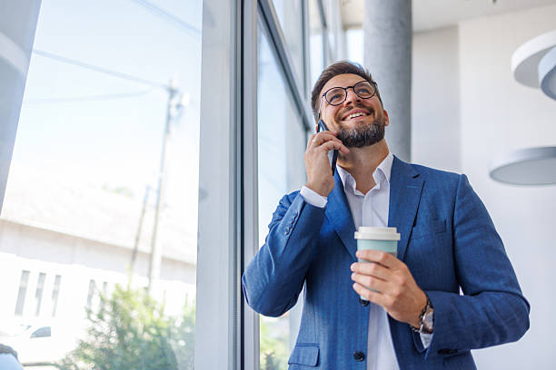 istock Businessman enjoys his coffee while making a phone call in a modern office 2234968725