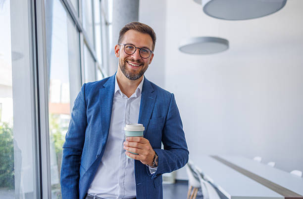 istock Smiling businessman holding coffee cup in modern office 2234968750