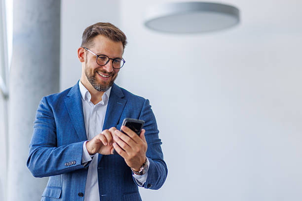 istock Smiling businessman using smartphone in modern office 2234968765