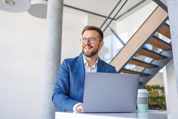istock Businessman smiling while working on laptop in modern office 2234971995