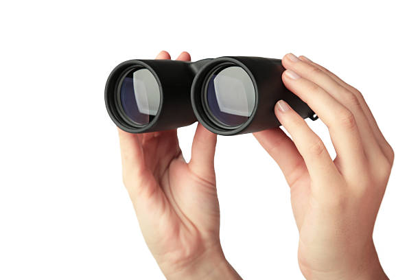 istock Female hand holds black binoculars isolated on white background. Looking through binoculars, journey, find and search concept 2234972309