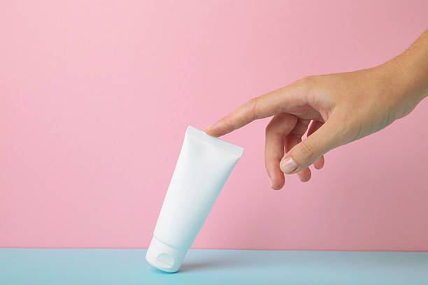 istock Hand holding blank white plastic tube on pink background. Space for text 2234972333