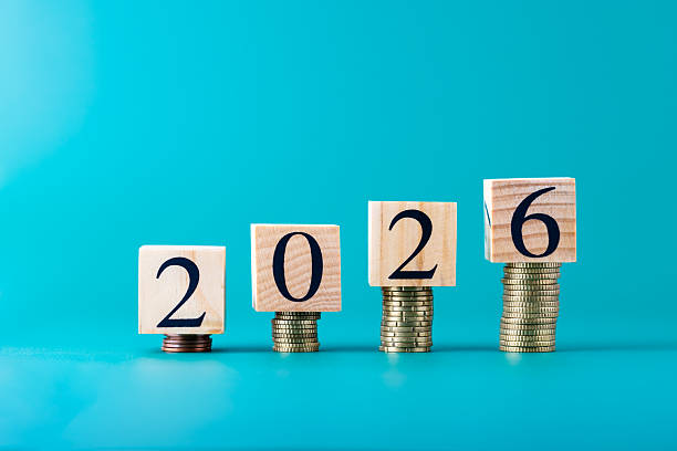 istock Wooden blocks with number 2026 placed on coin stacks over turquoise blue background, horizontal composition. Copy space. Concept of finance, savings, investment and business growth 2234973029