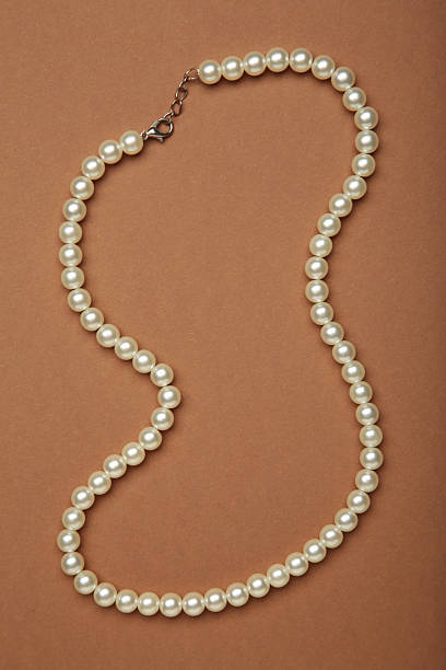 istock Elegant pearl necklace on brown background, top view. 2234973560