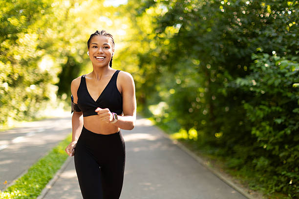 istock Confident young black female jogger smiling while running outdoors in park 2234981477