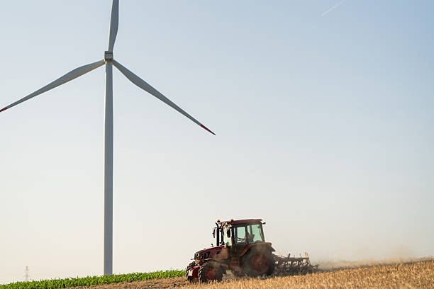 istock Agricultural tractor on the field with wind turbines. 2234985394