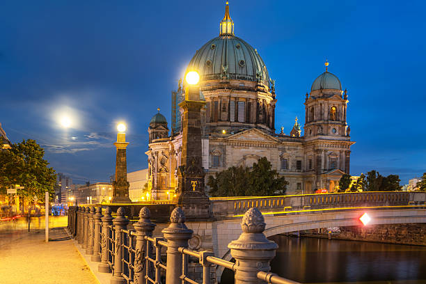A stunning night-time view of the Berlin Cathedral illuminated, showcasing its architectural splendor along with the serene nighttime setting and accompanying reflections.