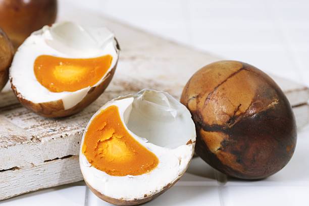 Close up photo of grilled salted egg cut open, showing orange yolk inside. Traditional Asian preserved egg snack.