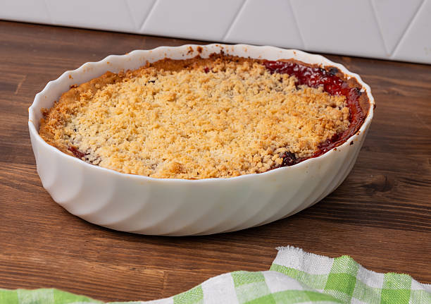 istock traditional plum crumble pie in white ceramic dish on wooden kitchen counter. 2234993898