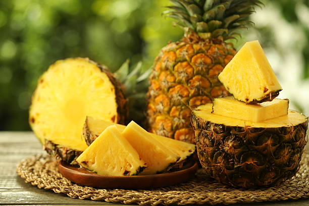 istock Fresh ripe pineapples on wooden table against blurred background, closeup 2234994340