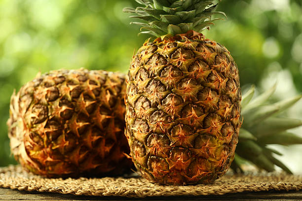 istock Fresh ripe pineapples on wooden table against blurred background, closeup 2234994343