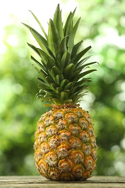 istock Fresh ripe pineapple on wooden table against blurred background 2234994348