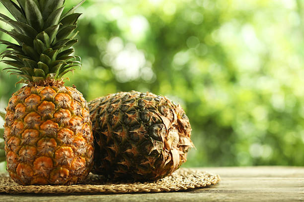 istock Fresh ripe pineapples on wooden table against blurred background, space for text 2234994417