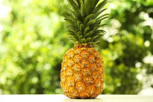 istock Fresh ripe pineapple on white wooden table against blurred background 2234994423
