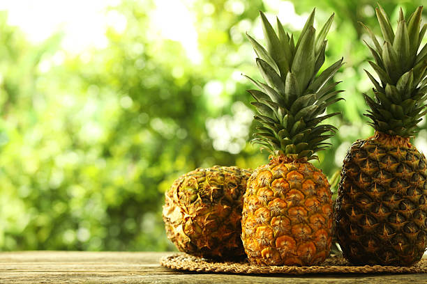 istock Fresh ripe pineapples on wooden table against blurred background, space for text 2234994425