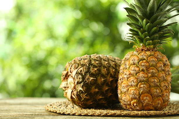 Fresh ripe pineapples on wooden table against blurred background, space for text