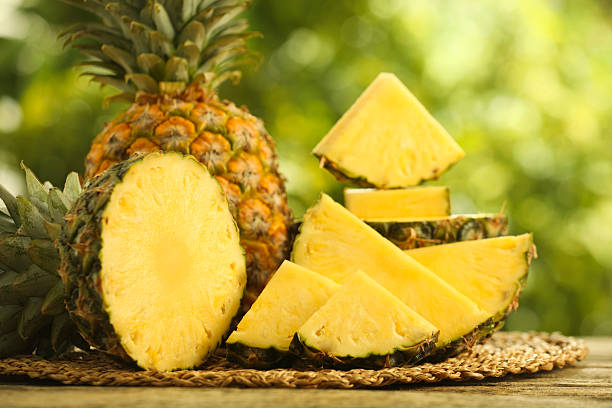istock Fresh ripe pineapples on wooden table against blurred background, closeup 2234994444