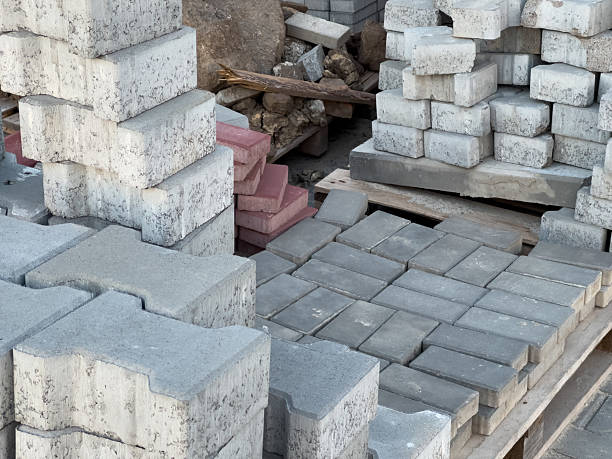 istock Stacked grey and red concrete paving blocks and bricks on wooden pallets. Construction materials for building roads and paths outdoors. 2234995295