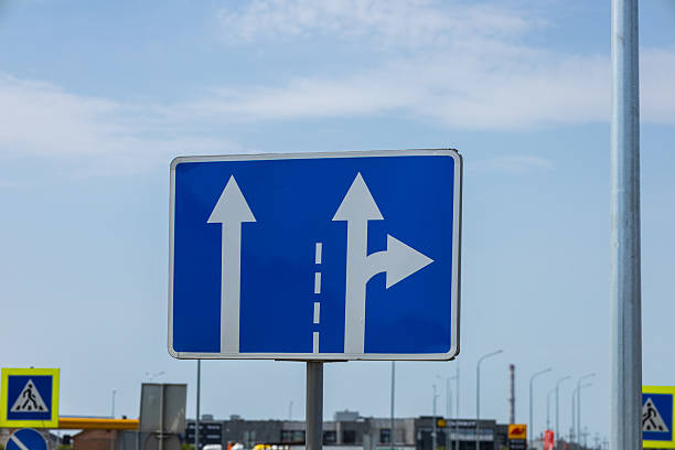 istock Blue rectangular road sign featuring white straight and right turn arrows providing directions under a bright sky. 2234995300