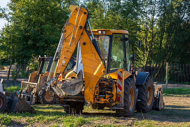Large yellow powerful backhoe loader parked outdoors on a construction site. Heavy machinery with big tires and dirty bucket on sunny day.