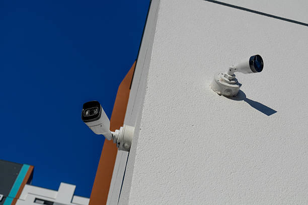 istock Two white security cameras mounted on textured building wall under a clear blue sky. Modern surveillance technology for urban security. 2234995339