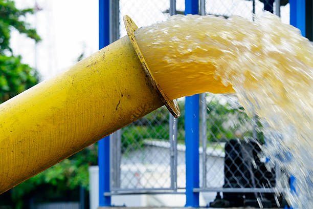 This vibrant image features a water pump setup against a bright yellow wall, showcasing pipes and industrial machinery in a utility area.