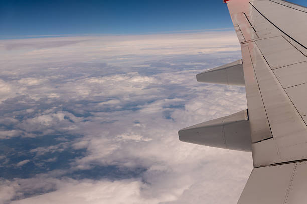 Airplane wing soaring above a breathtaking expanse of fluffy white clouds, creating a mesmerizing view during daytime