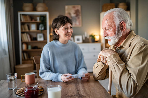 istock Nurse assisting elderly man with medication during home visit 2235000499