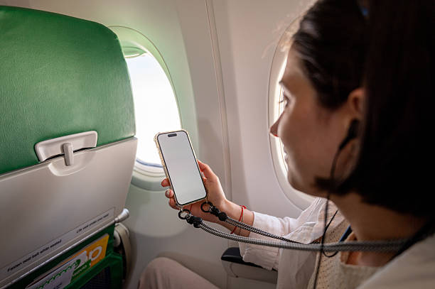istock Young woman using smartphone on airplane near window seat 2235001815