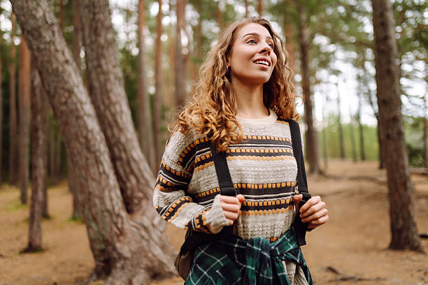 istock A beautiful woman with a backpack enjoys nature in the forest. 2235002722