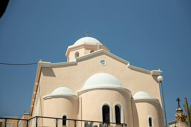 Greek orthodox church with multiple domes and crosses, bathed in sunlight under a clear blue sky