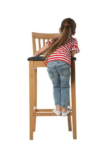 istock Little girl standing on stool against white background, back view 2235004362