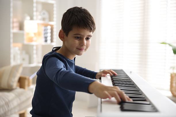 istock Cute boy playing synthesizer at home. Electronic musical instrument 2235005663