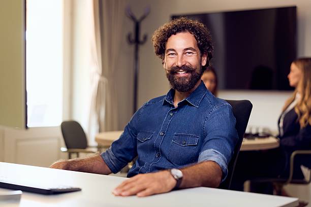 istock Smiling Man in Office Setting with Casual Attire and Professional Environment 2235007494