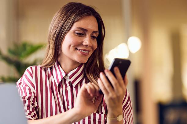 istock Smiling Woman Using Smartphone Properly in a Bright and Relaxing Environment 2235007531