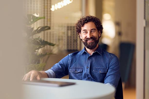 istock Smiling Bearded Man Sitting in a Modern Office Environment 2235007533