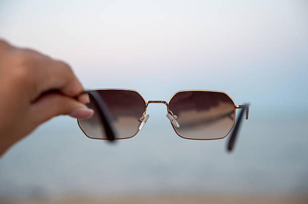 istock hand holding sunglasses against a beach backdrop 2235008214