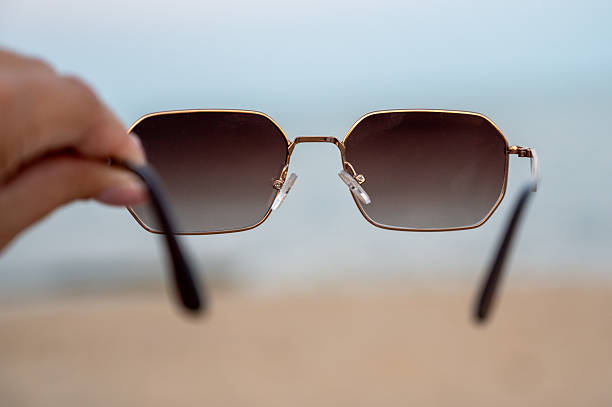 istock hand holding sunglasses against a beach backdrop 2235008223